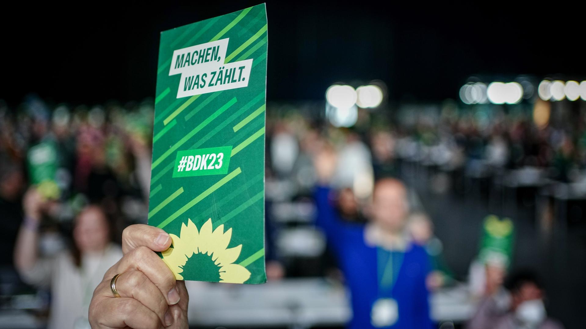 Blick auf eine erhobene Hand, die beim Bundesparteitag der Grünen in Karlsruhe einen Stimmzettel in die Höhe hält.