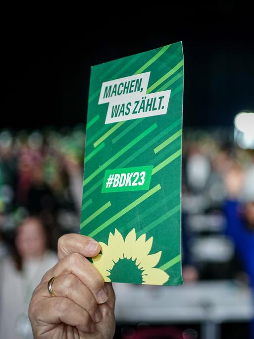 Blick auf eine erhobene Hand, die beim Bundesparteitag der Grünen in Karlsruhe einen Stimmzettel in die Höhe hält.