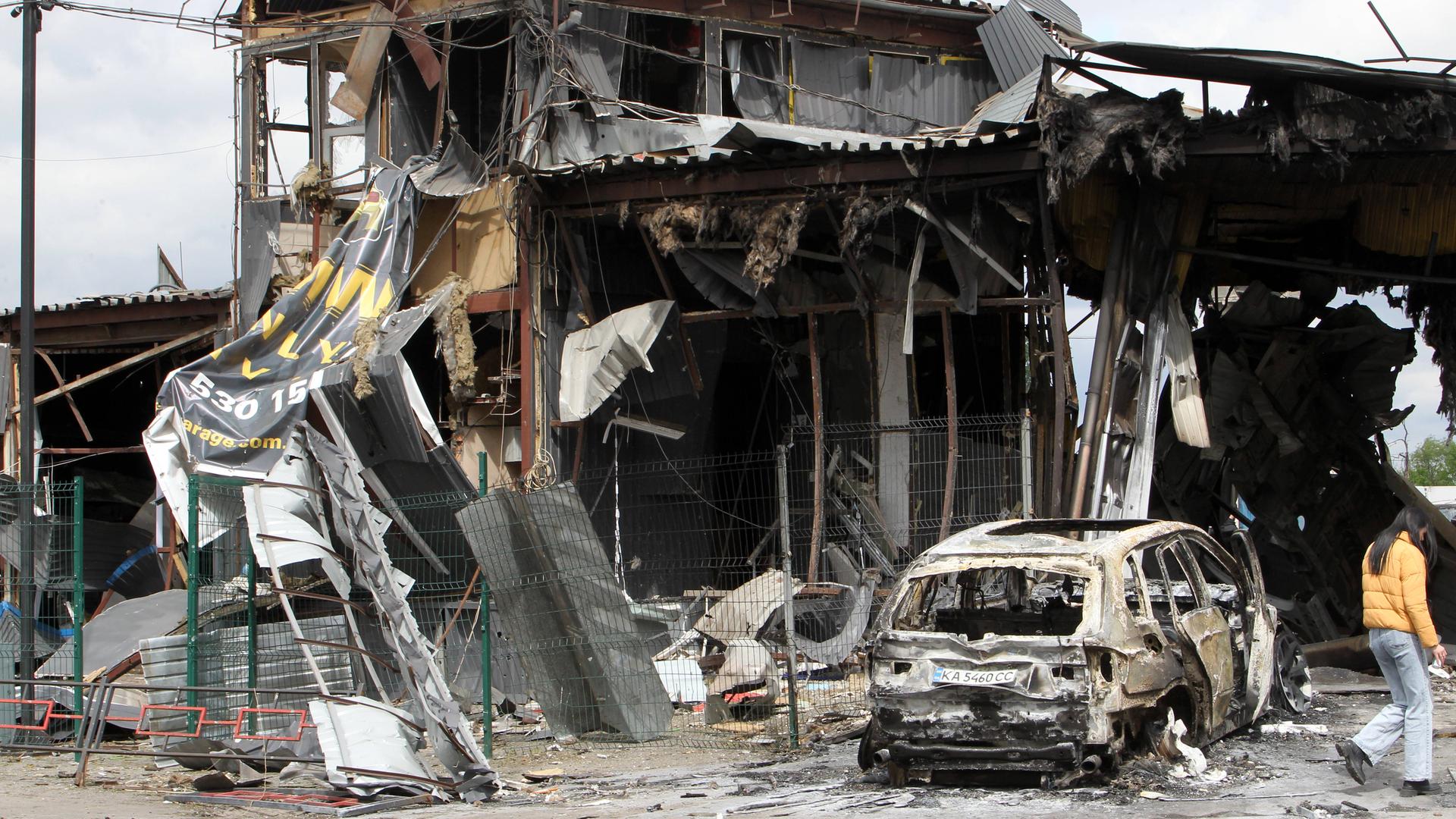 Ein ausgebrannter PKW steht vor einem zerstörten Gebäude. Aufnahme aus der ukrainischen Stadt Dnipro nach einem russischen Raketenangriff.