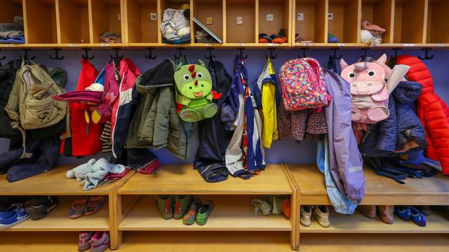 Mäntel, Jacken und Rucksäcke von Kindern hängen an einer Garderobe in einer Kita.