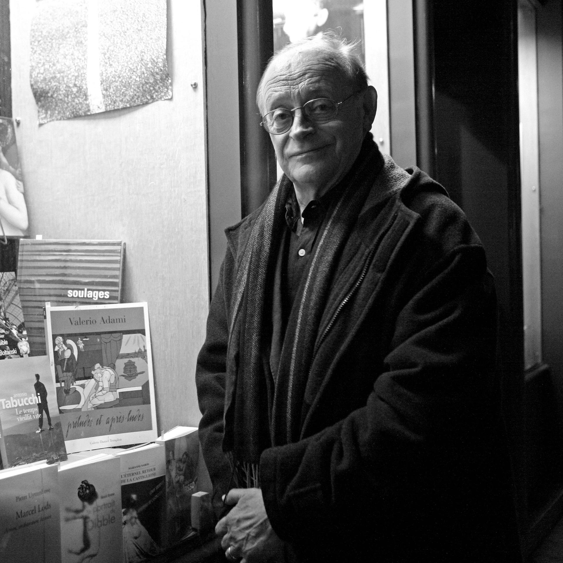 Schwarz-weiß-Porträt des italienischen Schriftstellers Antonio Tabucchi. Er steht vor einem Schaufenster mit Büchern in Paris. Das Bild stammt aus dem Jahr 2010.