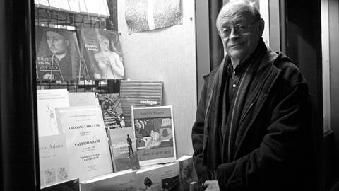 Schwarz-weiß-Porträt des italienischen Schriftstellers Antonio Tabucchi. Er steht vor einem Schaufenster mit Büchern in Paris. Das Bild stammt aus dem Jahr 2010.