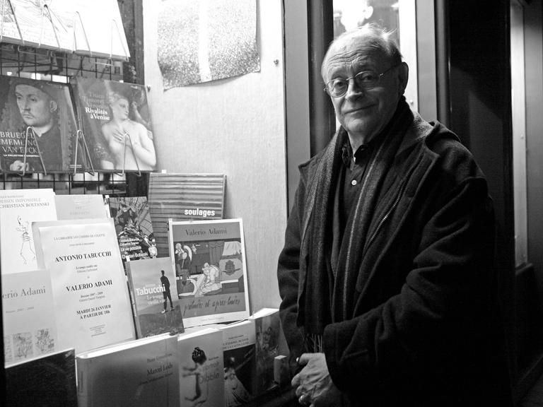 Schwarz-weiß-Porträt des italienischen Schriftstellers Antonio Tabucchi. Er steht vor einem Schaufenster mit Büchern in Paris. Das Bild stammt aus dem Jahr 2010.