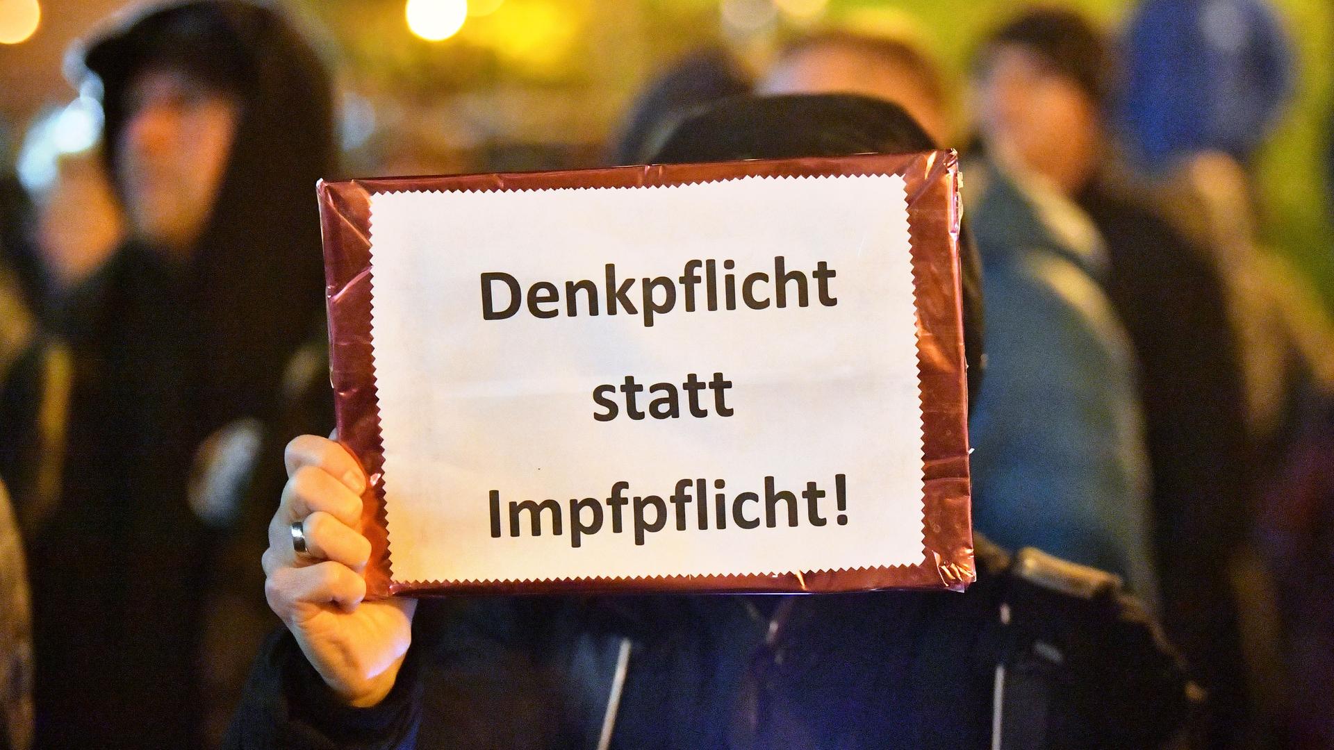 "Denkpflicht statt Impfpflichtt" steht auf dem Plakat, das eine Frau bei einer Demonstration vor dem Thüringer Landtag in den Händen hält