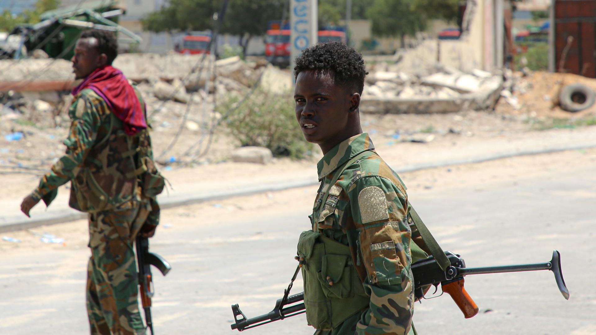 Mitglieder der somalischen Armee auf einer Straße in Mogadischu mit einer Waffe umgehängt.