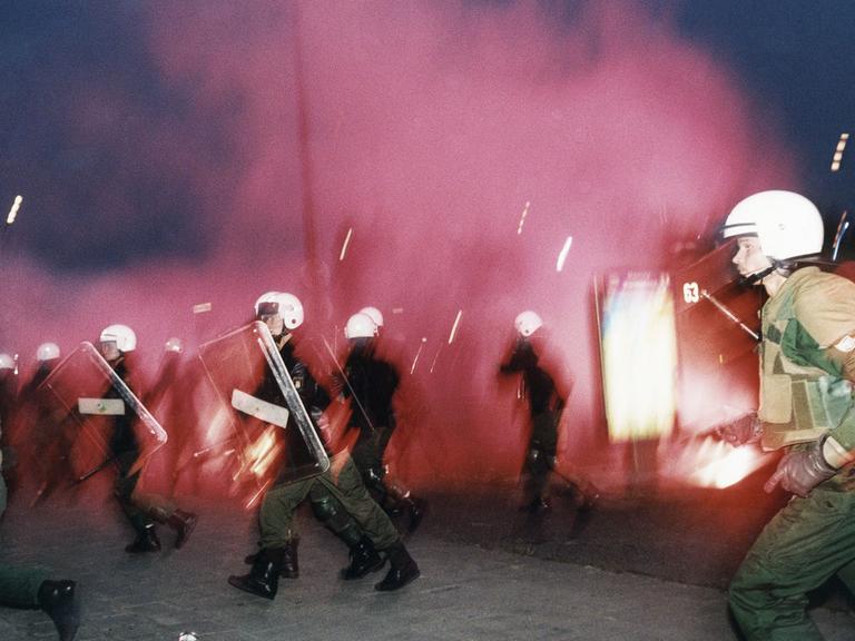 Polizisten rennen während eines rassisitischen Anschlages mit Molotow-Cocktails in Rostock-Lichtenhagen vor 30 Jahren.
