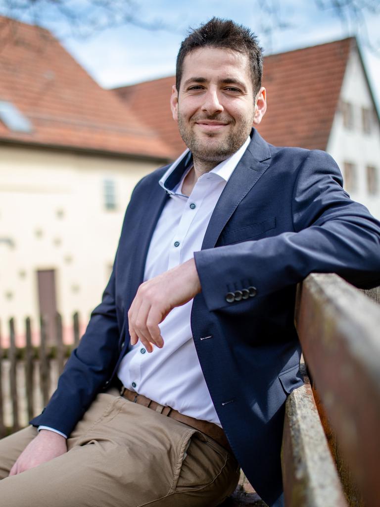 Ryyan Alshebl sitzt auf einer Bank und schaut freundlich in die Kamera.