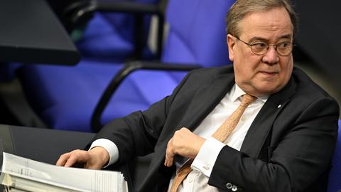 Armin Laschet (CDU) sitzt im Plenarsaal des Bundestag vor einem Aktenstapel.