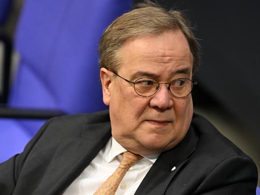 Armin Laschet (CDU) sitzt im Plenarsaal des Bundestag vor einem Aktenstapel.