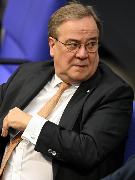 Armin Laschet (CDU) sitzt im Plenarsaal des Bundestag vor einem Aktenstapel.