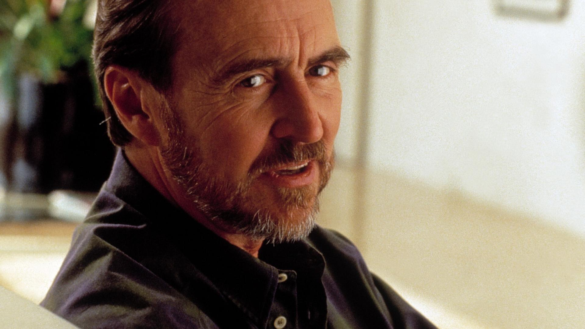 Der Regisseur Wes Craven sitzt in einem Foto von 1994 auf einem Sofa und schaut über seine rechte Schulter in die Kamera Der Regisseur Wes Craven sitzt in einem Foto von 1994 auf einem Sofa und schaut über seine rechte Schulter in die Kamera