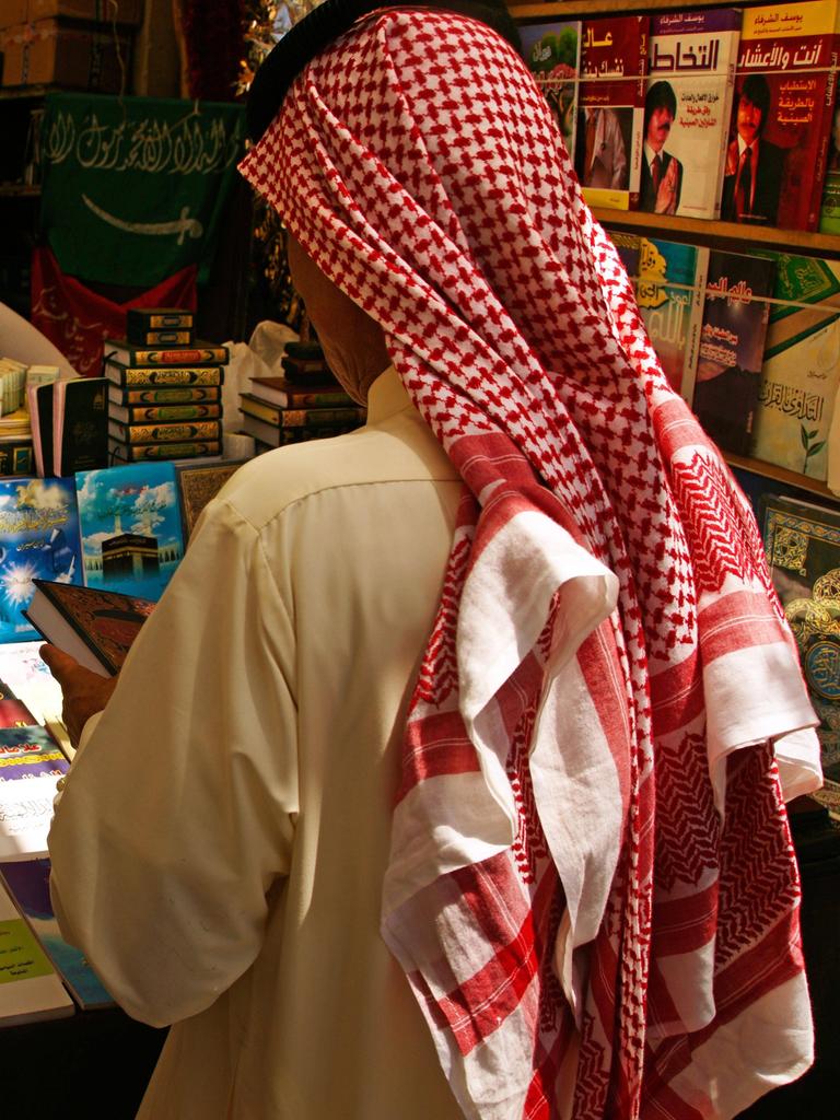  Ein Mann mit Kufiya von hinten. Er steht vor einem Stand mit vielen Büchern. 