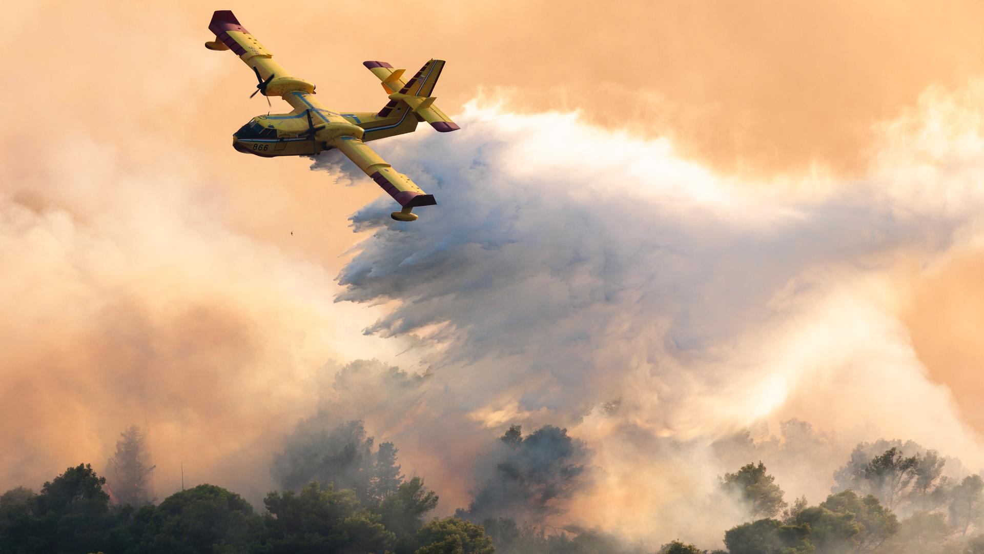 Ein Löschflugzeug versprüht Wasser, um einen Waldbrand in Kroatien zu löschen. Ein Löschflugzeug versprüht Wasser, um einen Waldbrand in Kroatien zu löschen.