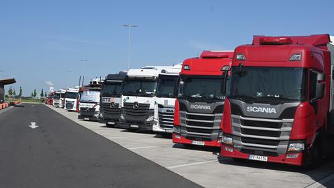 LKW's stehen nebeneinander auf einem Parkplatz an der Autobahn.