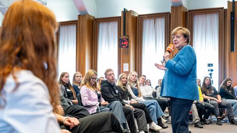 14.10.2026 Aufzeichnung der ersten Folge der Reihe „Merkel unplugged“. Angela Merkel steht vor Schülerinnen und Schülern und hat ein Mikrofon in der Hand. 14.10.2026 Aufzeichnung der ersten Folge der Reihe „Merkel unplugged“. Angela Merkel steht vor Schülerinnen und Schülern und hat ein Mikrofon in der Hand.