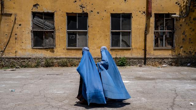 Afghanische Frauen in Burkas gehen an einer zerstörten Hauswand in Kabul vorbei.
