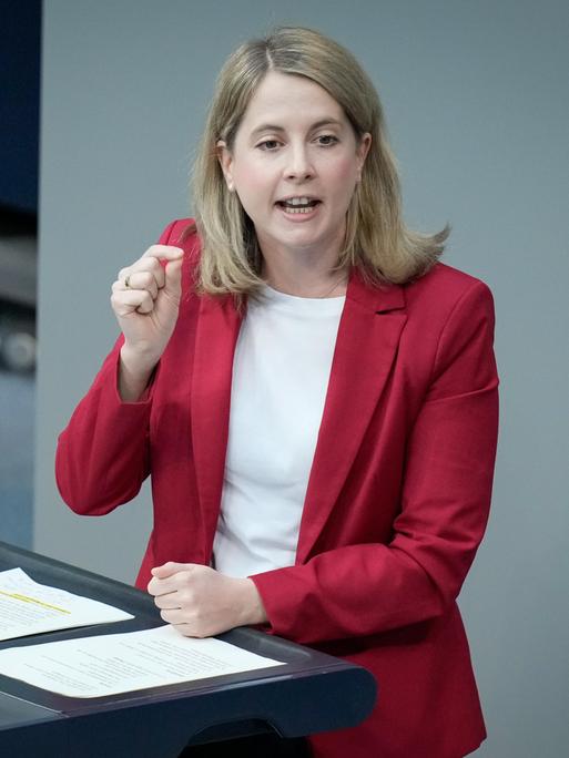 Verena Hubertz, in einem roten Sakko, spricht am Rednerpult des Deutschen Bundestags.