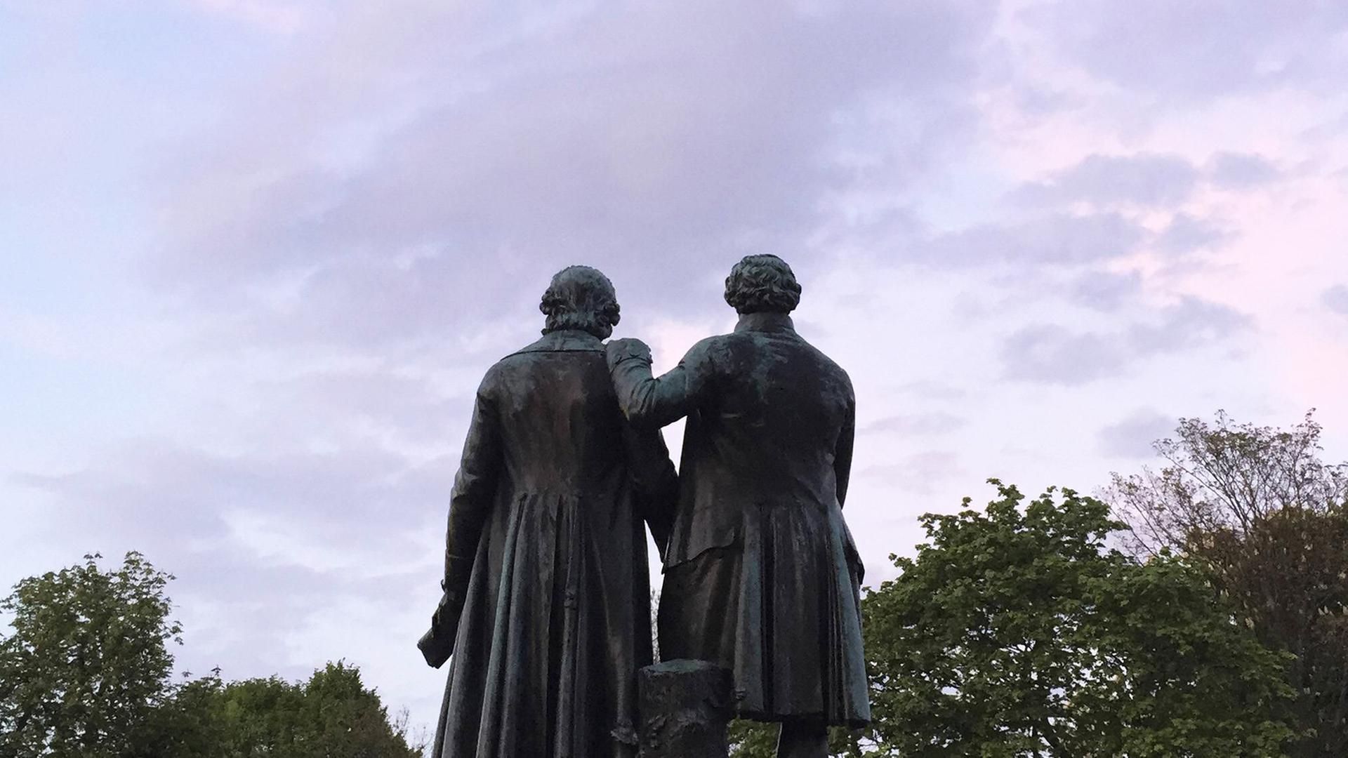 Das Goethe und Schiller Denkmal in Weimar, eine Figur legt die Hand auf die Schulter der anderen Figur.