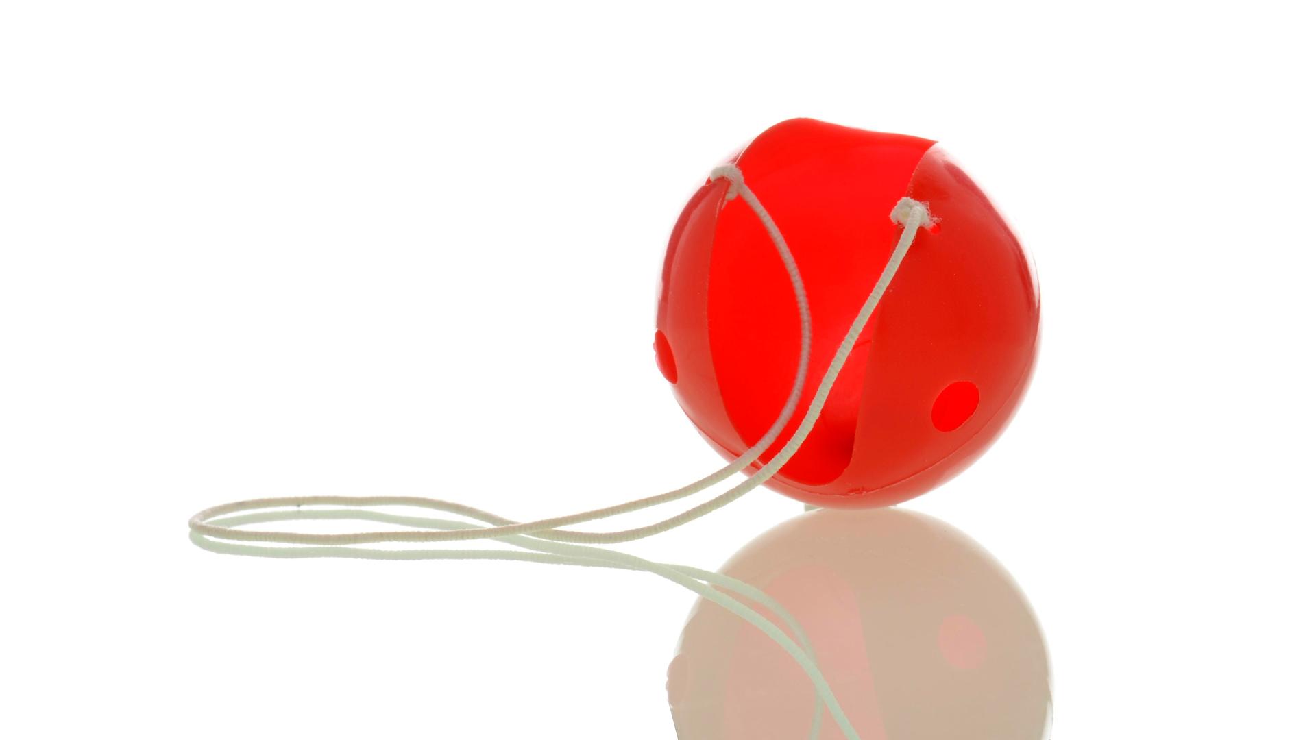 Eine rote Clownsnase an einem weißen Gummiband