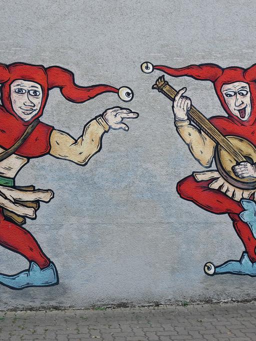 Zwei Hofnarren sind als Graffiti an einer Wand angebracht.  