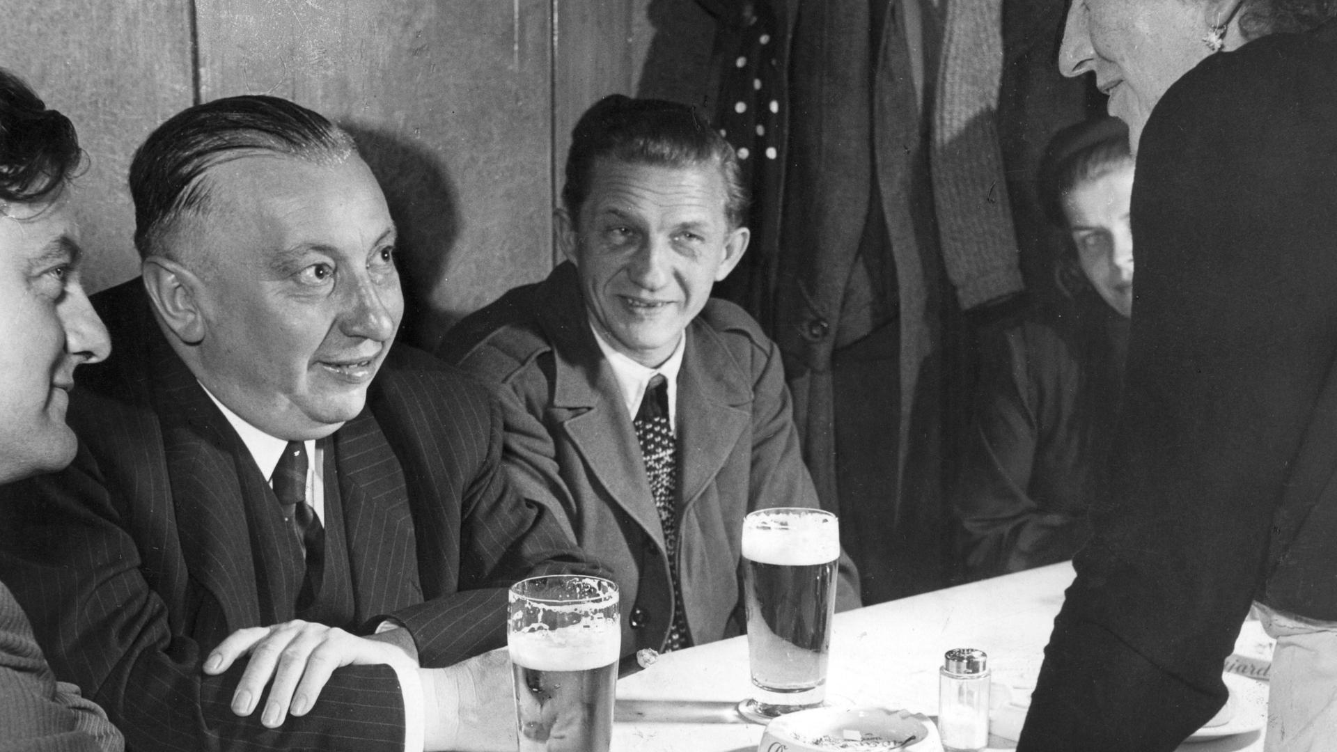 Ein Schwarz-Weiß-Foto zeigt den damaligen CSU-Vorsitzenden Josef Müller (2.v.li.) beim Bier trinken mit seinem jungen Mitarbeiter Franz Josef Strauß (1.v.li.).