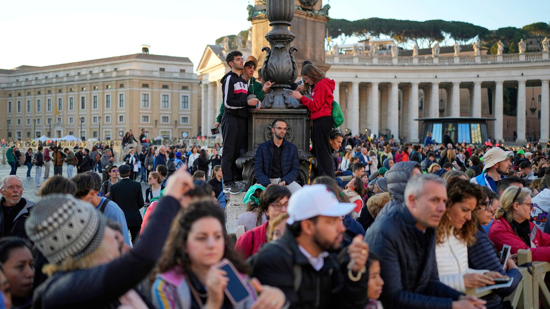 Das Bild zeigt zahlreiche Menschen, die am frühen Morgen zum Petersplatz gekommen sind, um an den Beerdigungsfeierlichkeiten für Papst Franziskus teilzunehmen. 