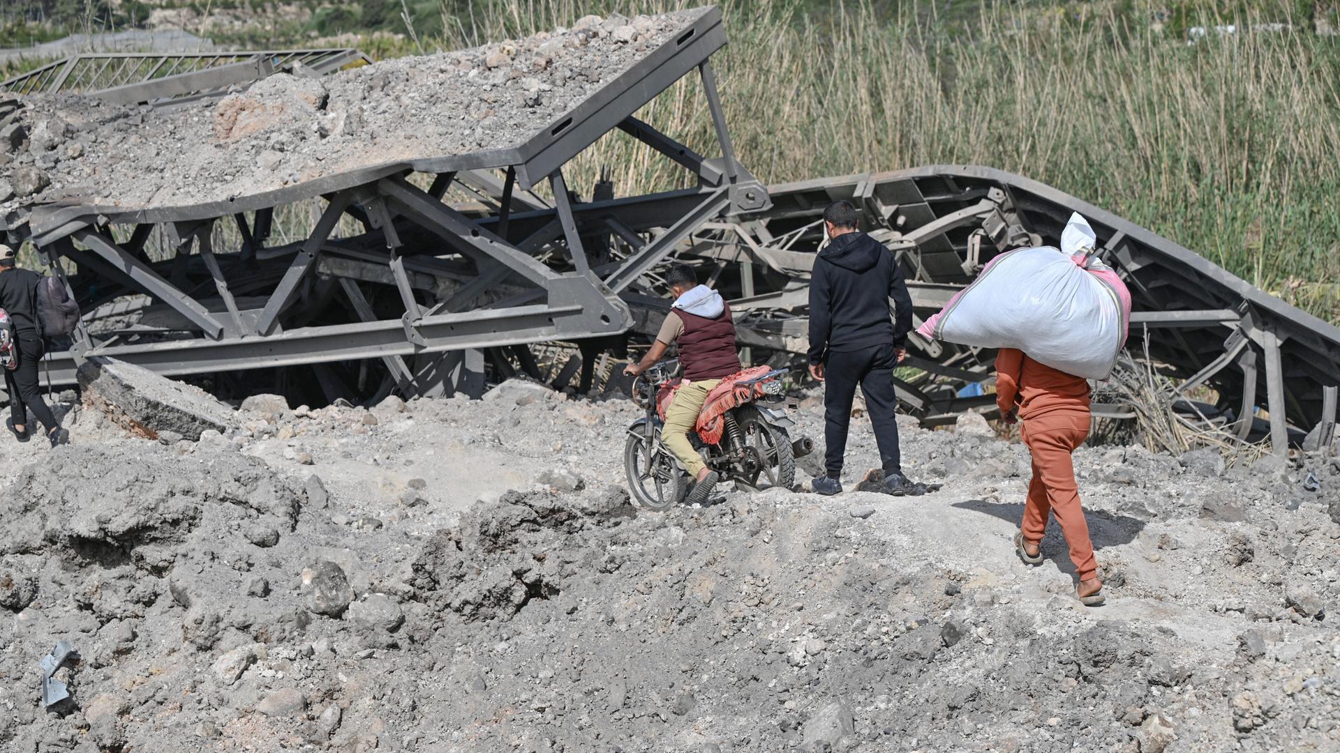 Libanesen versuchen über das Geröll zu steigen, das von der Qasimiyeh Brücke nach israelischen Angriffen übrig geblieben ist 