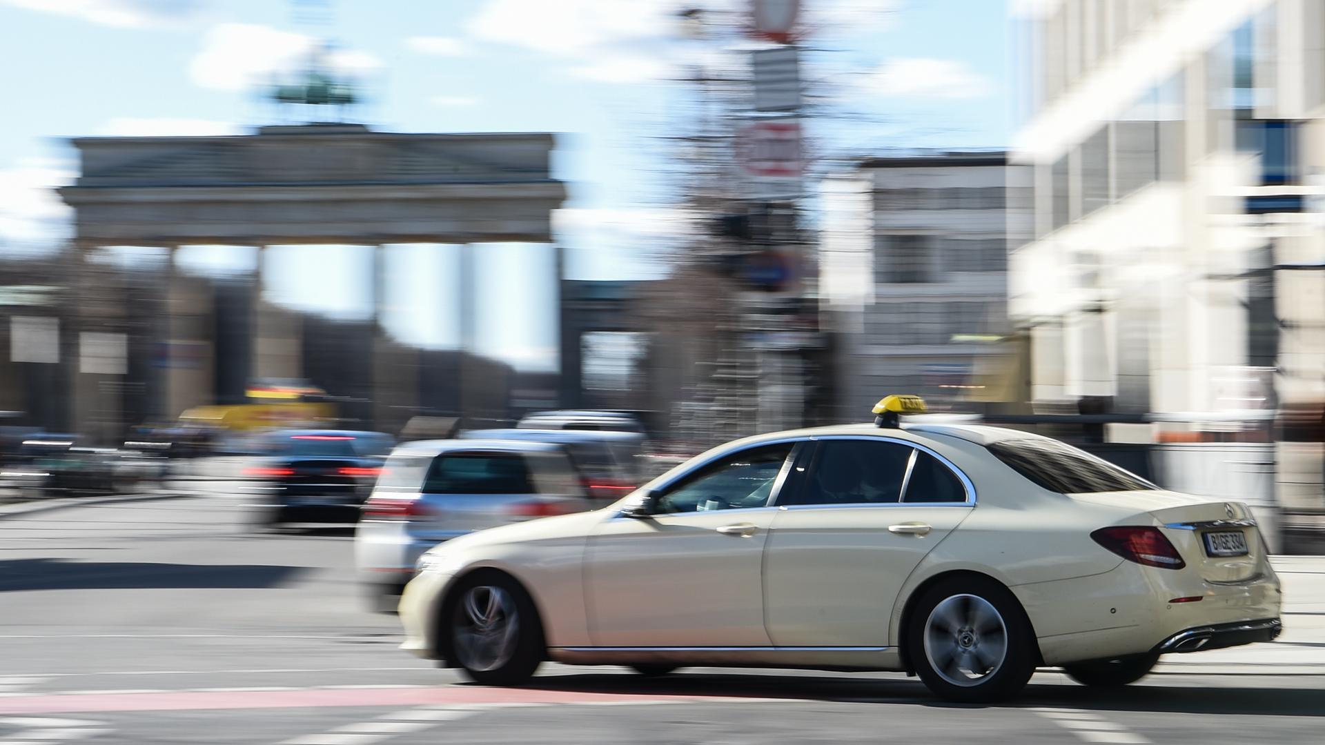 Ein Taxi fährt vor dem Brandenburger Tor entlang. 