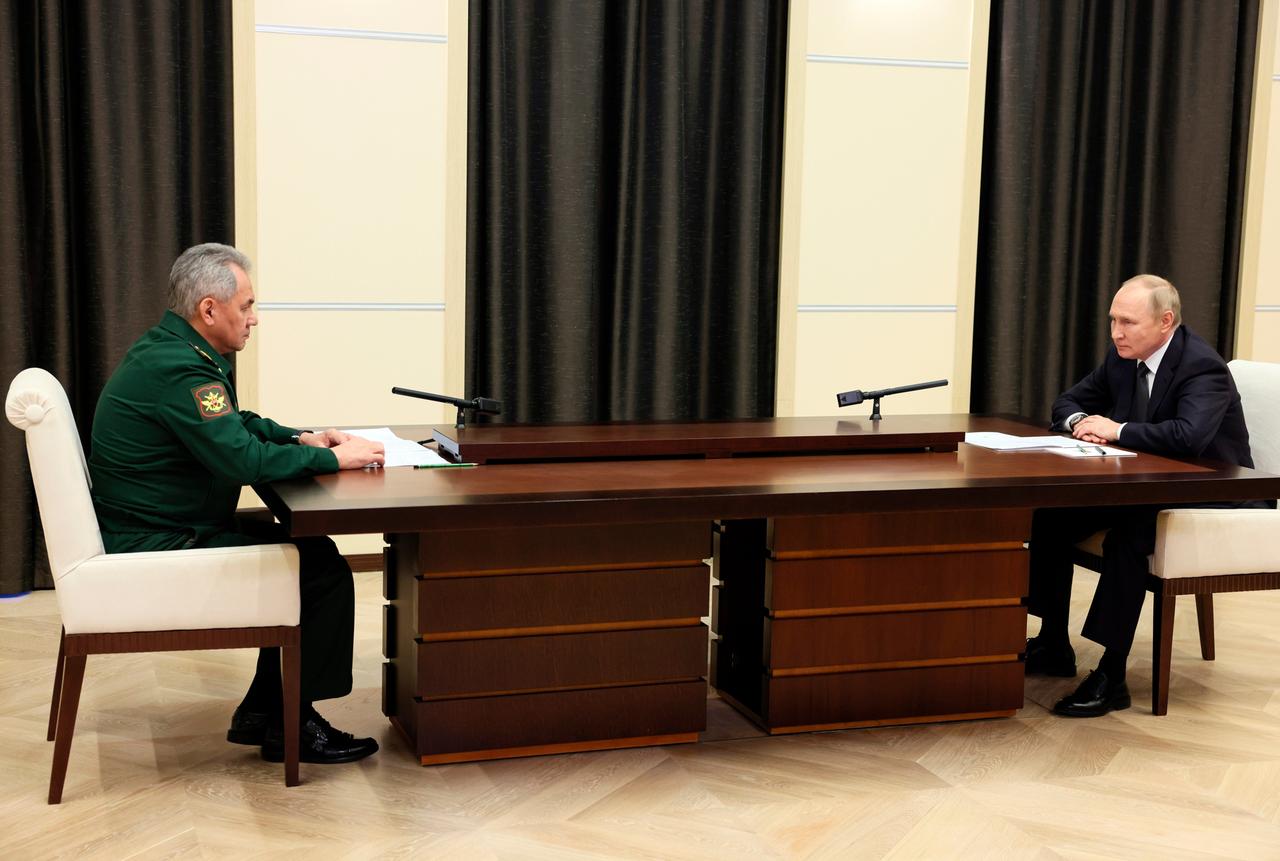 Russlands Präsident Wladimir Putin während eines Treffens mit Verteidigungsminister Sergej Schoigu in der Novo-Ogaryovo-Residenz. Die beiden sitzen sich mit großem Abstand an eine Tisch gegenüber.