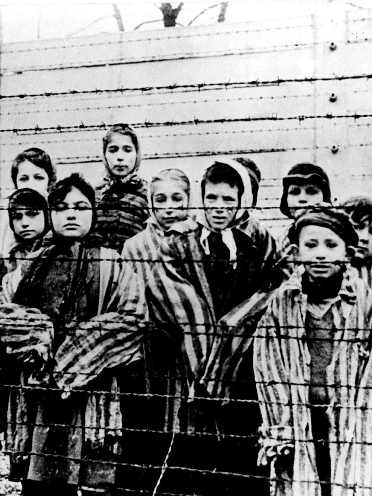 Kinder in Häftlingskleidung hinter einem Stacheldrahtzaun nach der Befreiung des Vernichtungslagers Ausschwitz durch die Rote Armee 1945.