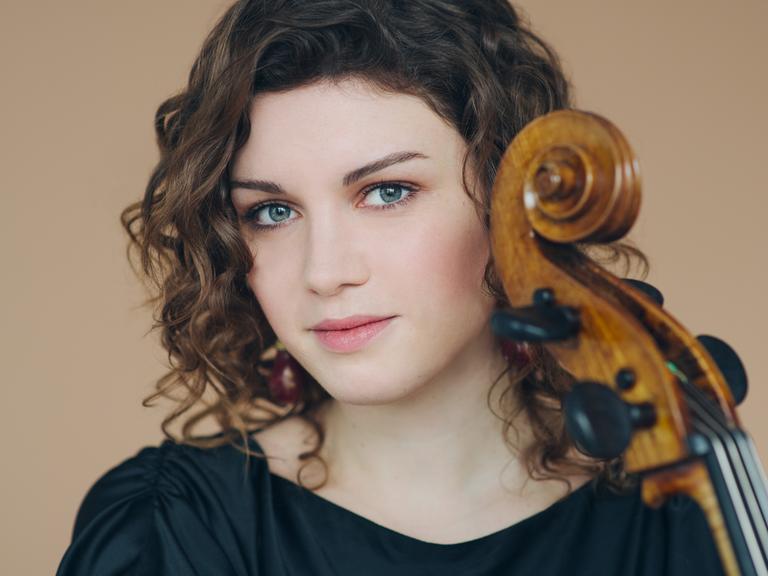 Porträtfoto von Julia Hagen, die ihr Violoncello nah an ihr Gesicht herangelassen hat.