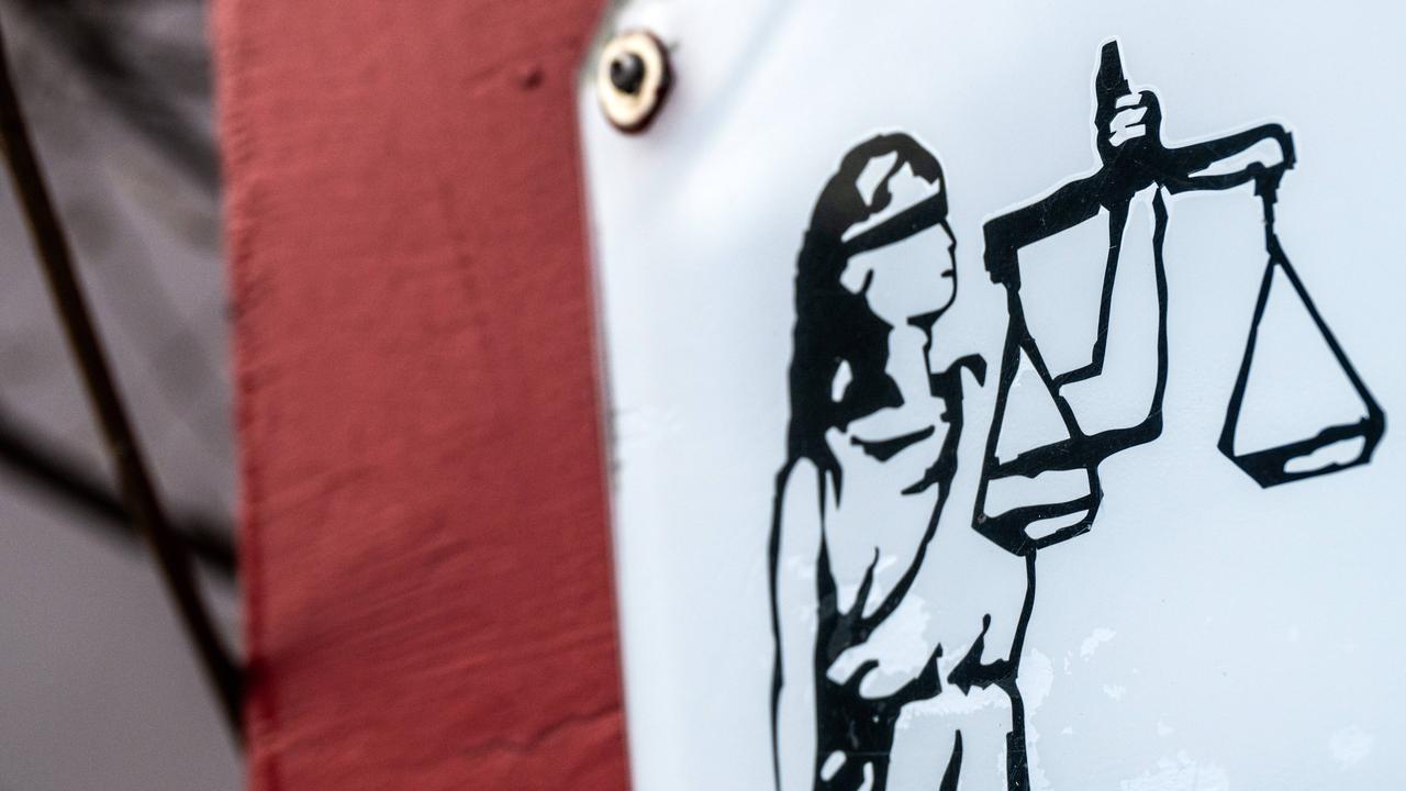 Eine grafische Darstellung der Justitia mit Augenbinde und Waage ist auf einem Schild zu sehen. Eine grafische Darstellung der Justitia mit Augenbinde und Waage ist auf einem Schild zu sehen.