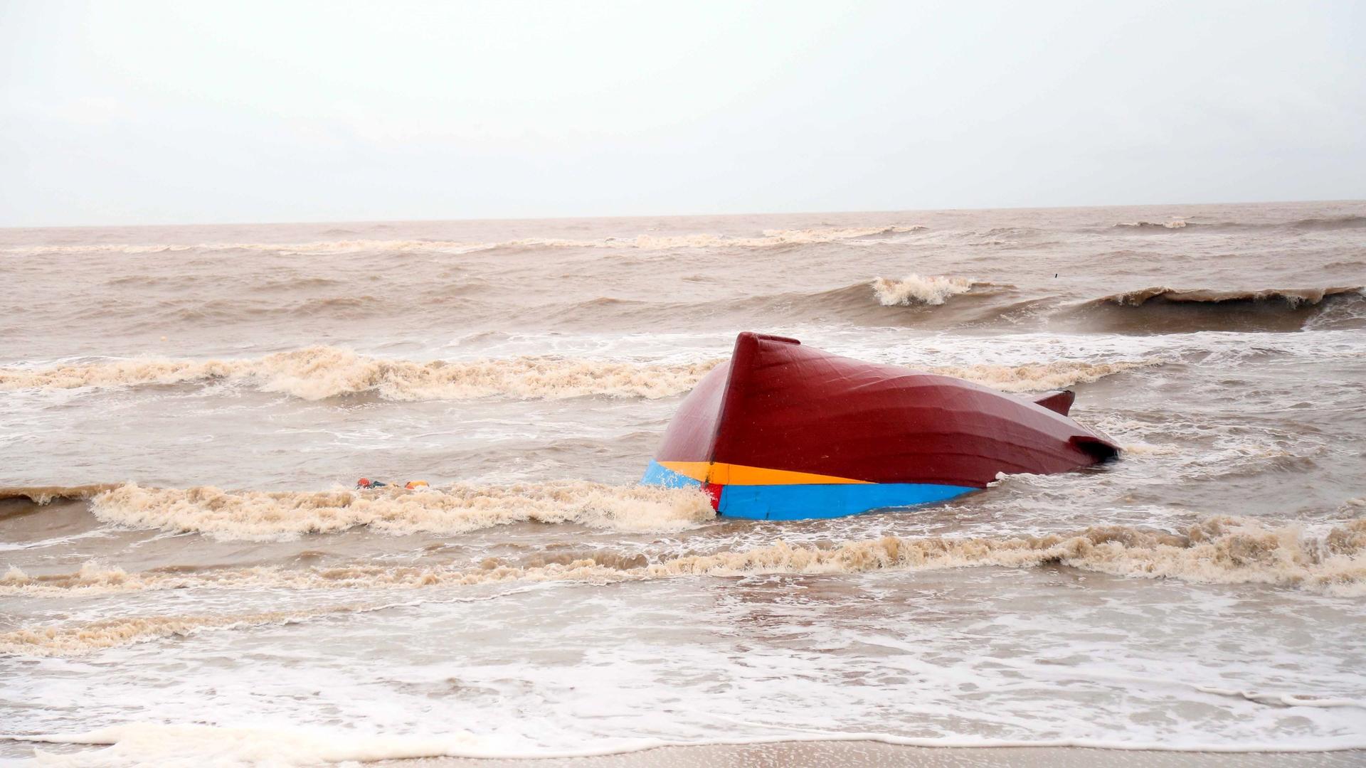 Ein gekentertes Boot treibt im aufgewühlten Meer.