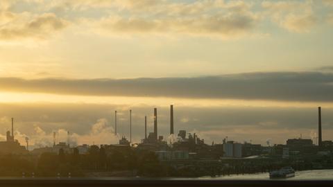 Rauchende Schornsteine unter dem Abendhimmel im Industriegebiet Chempark bei Leverkusen.