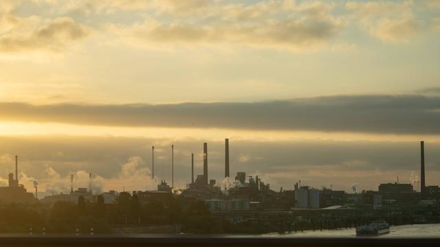 Rauchende Schornsteine unter dem Abendhimmel im Industriegebiet Chempark bei Leverkusen.