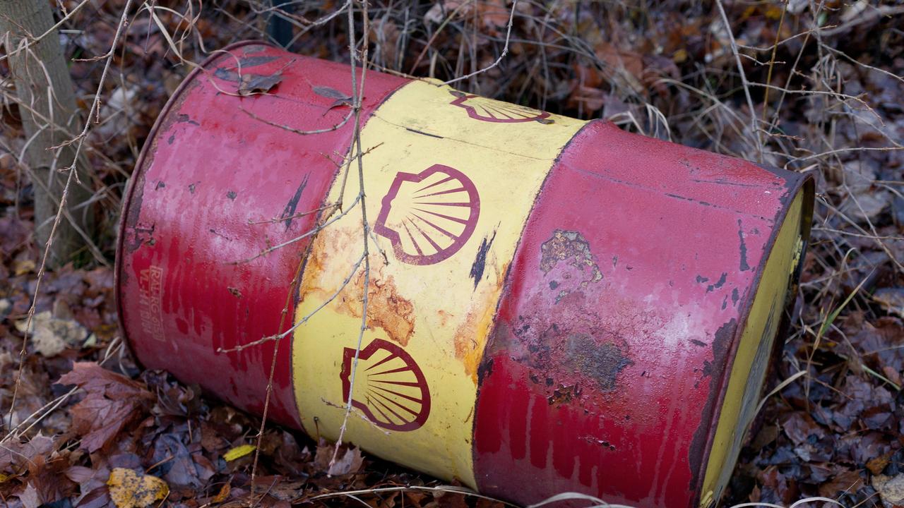 Ein altes, rostiges Ölfass mit dem Shell-Logo liegt auf einem von Laub bedeckten Boden
