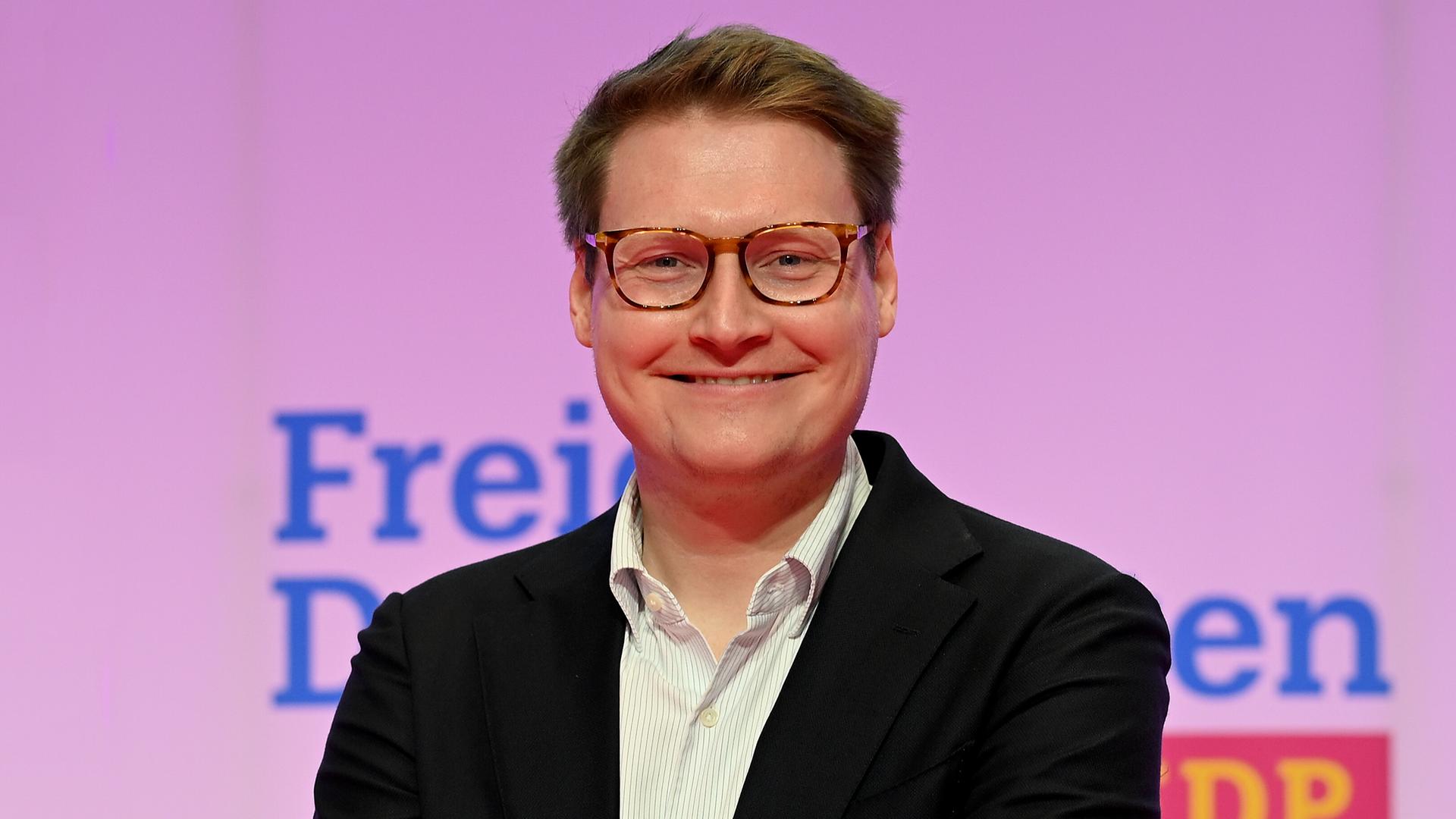 Moritz Körner (Mitglied des Europäischen Parlaments) steht vor einer Wand und lächelt. 