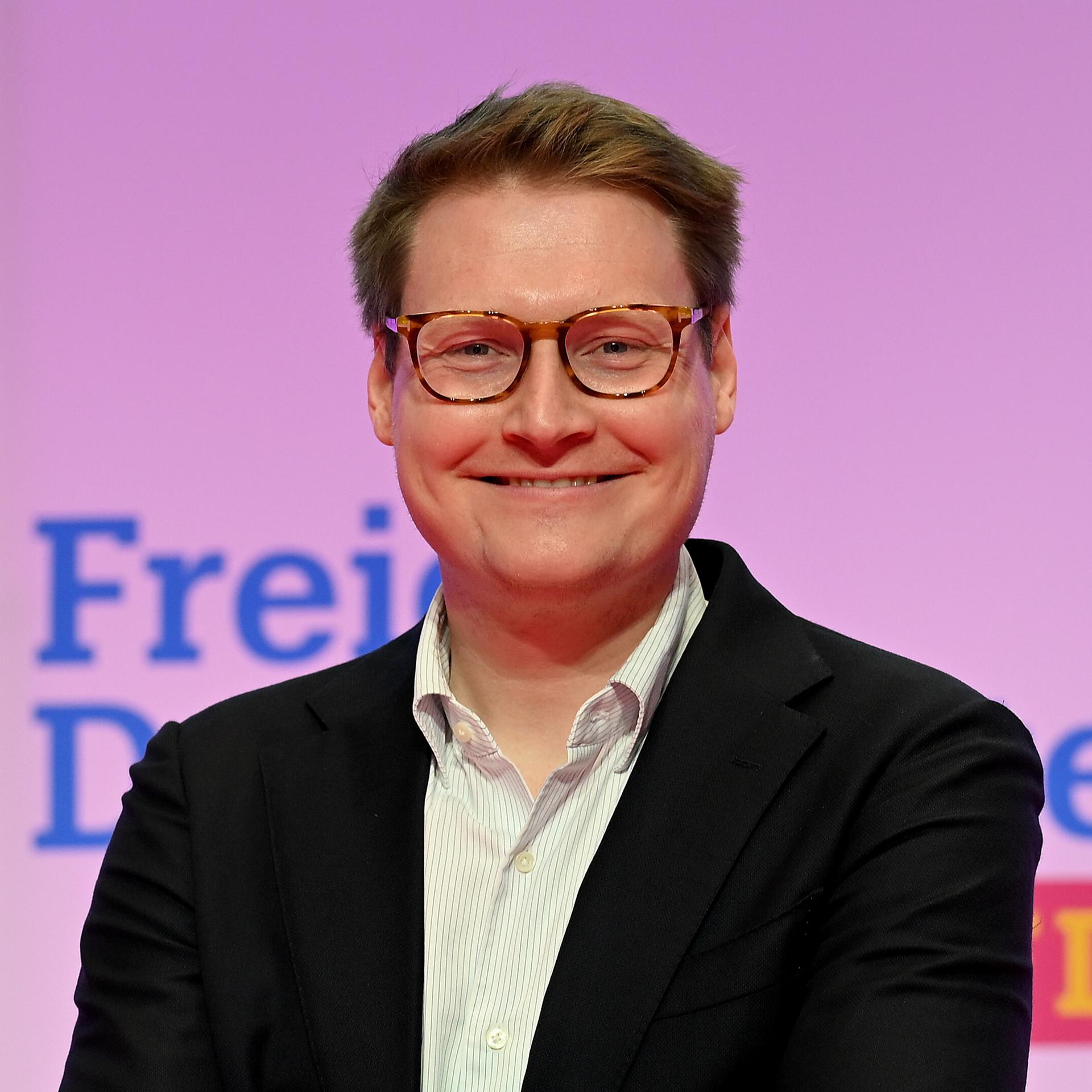 Moritz Körner (Mitglied des Europäischen Parlaments) steht vor einer Wand und lächelt. 