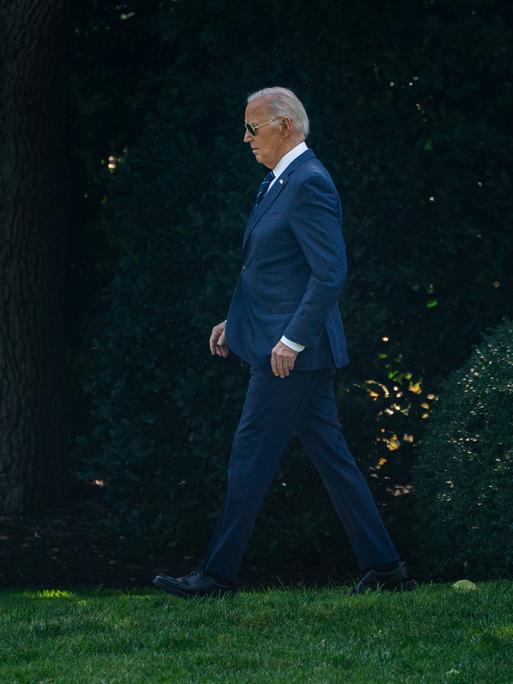 US-Präsident Joe Biden läuft alleine über eine Wiese mit Bäumen im Hintergrund in der Nähe des Oval Office in Washington am 15.7.2024.