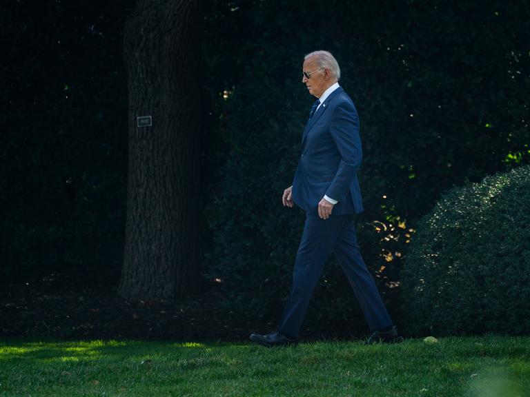 US-Präsident Joe Biden läuft alleine über eine Wiese mit Bäumen im Hintergrund in der Nähe des Oval Office in Washington am 15.7.2024.