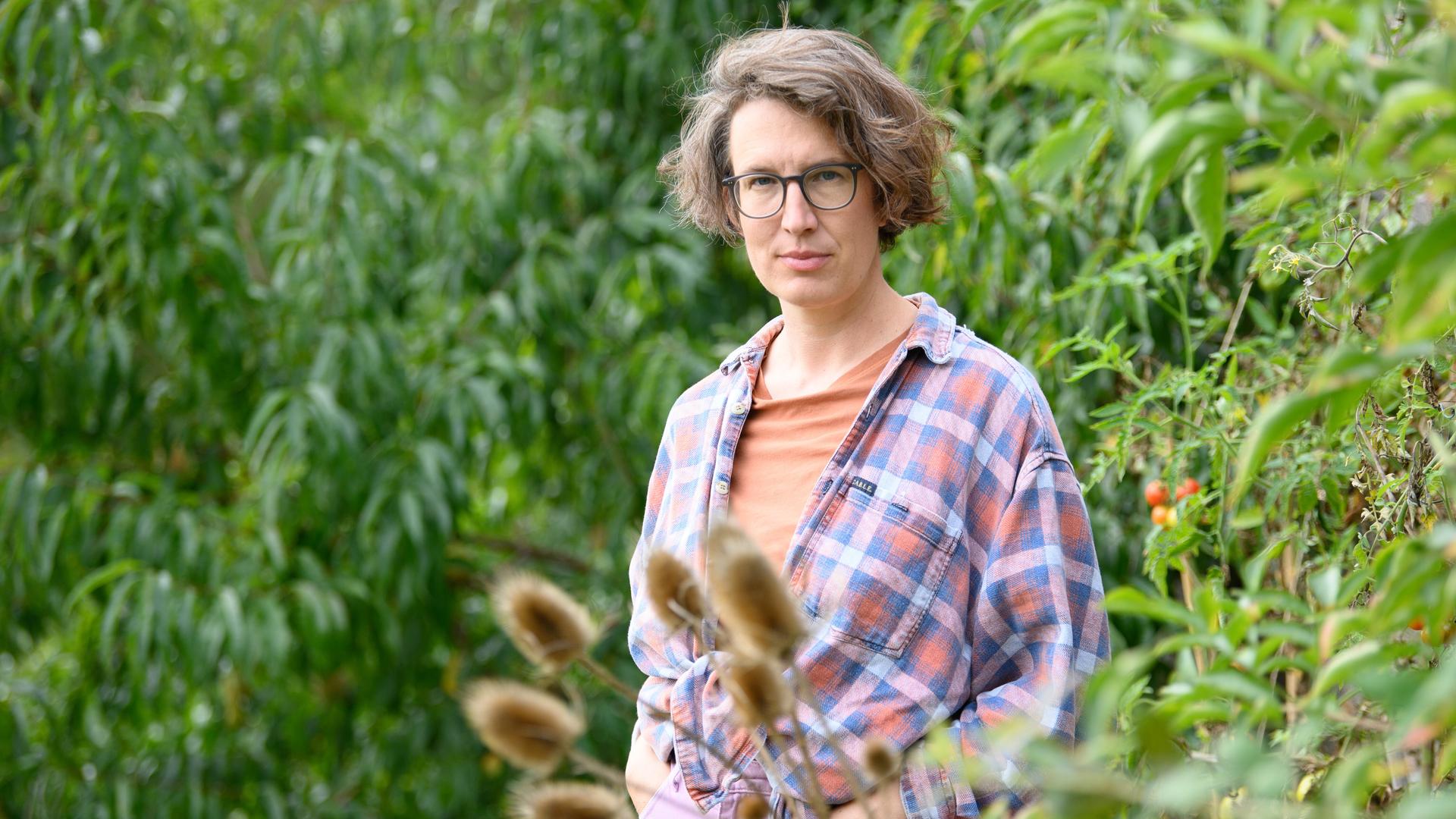 Die Autorin und Filmemacherin Lola Randl steht in ihrem Garten. 