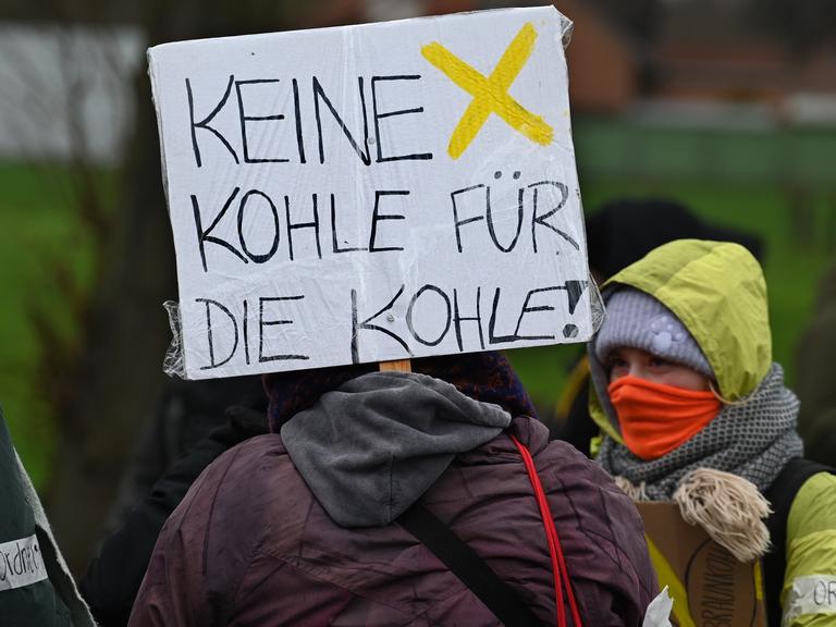 Demonstranten halten ein Schild mit der Aufschrift "Keine Kohle für die Kohle" auf einer Demonstration am 14.01.2023 bei Lützerath hoch