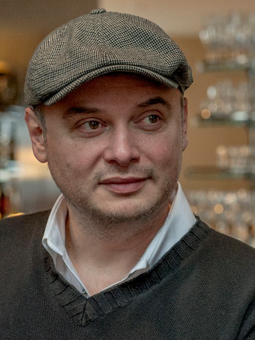 Porträt des aus Rumänien stammenden Schweizer Schriftstellers Catalin Dorian Florescu. Er trägt eine Schiebermütze und schaut schelmisch zur Seite. 