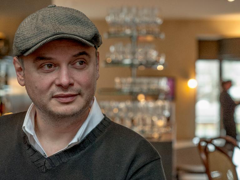 Porträt des aus Rumänien stammenden Schweizer Schriftstellers Catalin Dorian Florescu. Er trägt eine Schiebermütze und schaut schelmisch zur Seite. 
