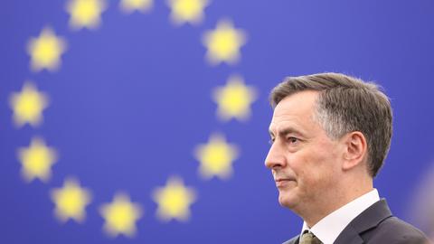 David McAllister steht vor einer blauen Wand, auf der ein Kreis aus gelben Sternen zu sehen ist.