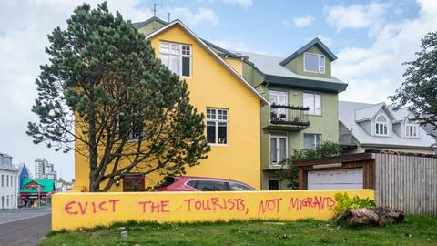 Der Slogan "Evict the tourists not the migrants" ("Die Touristen ausweisen, nicht die Migranten") steht auf einer Mauer eines Wohnhauses in Reykjavik, Island 2023.