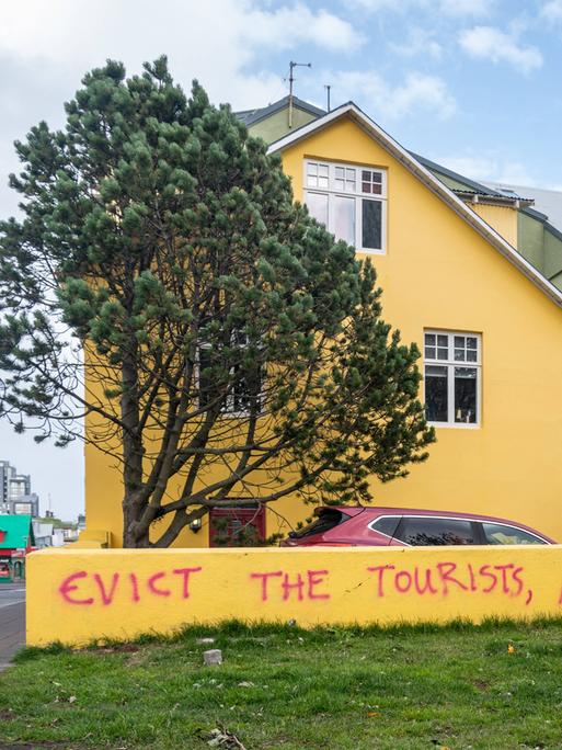 Der Slogan "Evict the tourists not the migrants" ("Die Touristen ausweisen, nicht die Migranten") steht auf einer Mauer eines Wohnhauses in Reykjavik, Island 2023.