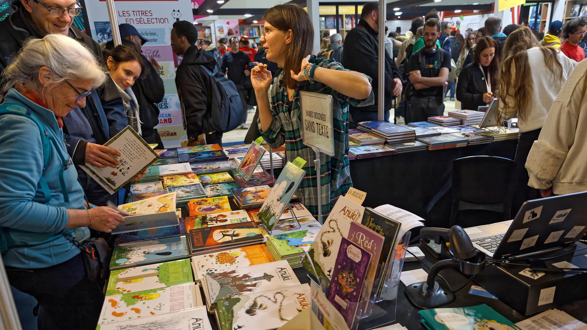 Comicfans blättern an Büchertischen in Comicbüchern.