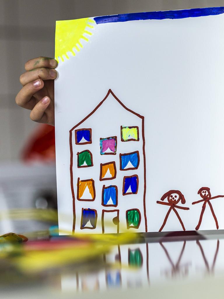 Eine Kinderhand hält eine Zeichnung von einem Haus