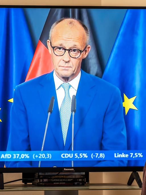 TV-Zuschauerin vor einem Fernsehgerät daheim: Rede von Bundeskanzler Friedrich Merz nach den ersten Prognosen zu den Landtagswahlen in Berlin und Mecklenburg-Vorpommern. TV-Zuschauerin vor einem Fernsehgerät daheim: Rede von Bundeskanzler Friedrich Merz nach den ersten Prognosen zu den Landtagswahlen in Berlin und Mecklenburg-Vorpommern.
